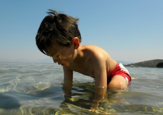 D kneeling in the water on the sandbar